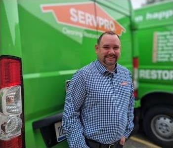 Male employee, Jerry, standing in front of green SERVPRO vehicle