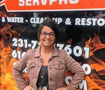 Female employee, dark hair and glasses standing in front of SERVPRO fire/water trailer