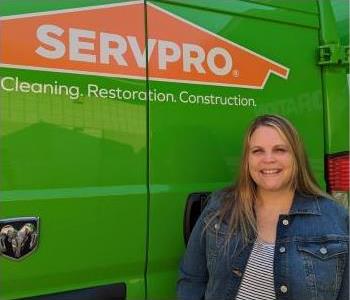 Female employee, Mandy, standing in front of green SERVPRO vehicle