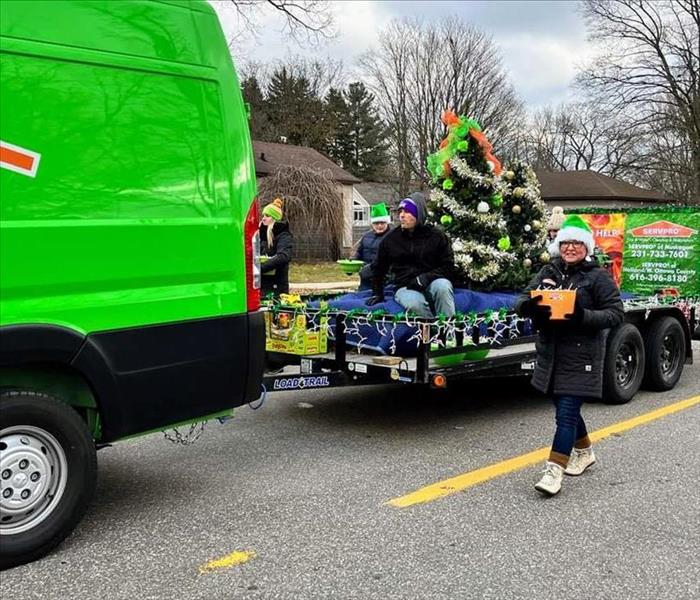 SERVPRO vehicle pulling decorated float with walkers passing out candy