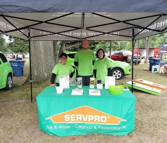 SERVPRO of Muskegon marketing team posing behind their booth at Sportsmen for Youth-Youth Day.