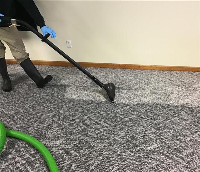 Extracting water from wet basement carpet after a flood.