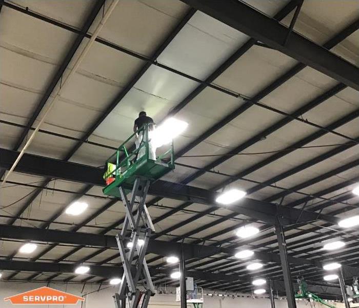 Male technician on scissor lift cleaning ceiling