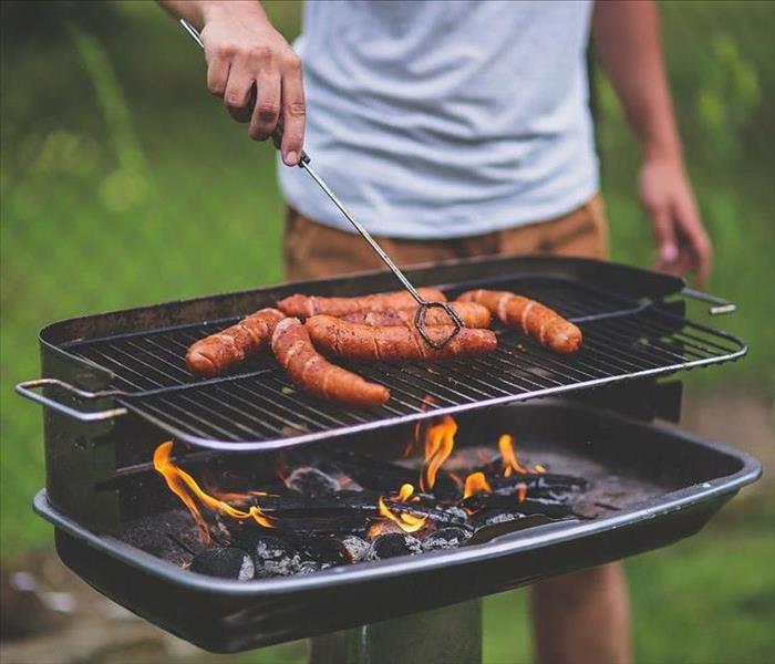 Male grilling hot dogs on charcoal grill